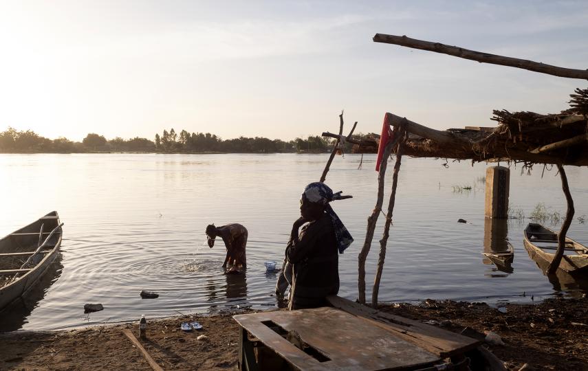 A scene at the water's edge with boats and a low lying sun