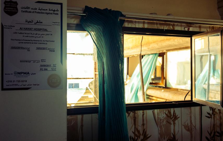 Hospital curtains blow through broken windows of a destroyed hospital.