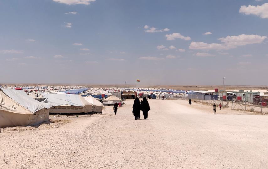 Photo of al-Hol camp in Syria showing a dry landscape and temporary shelters.