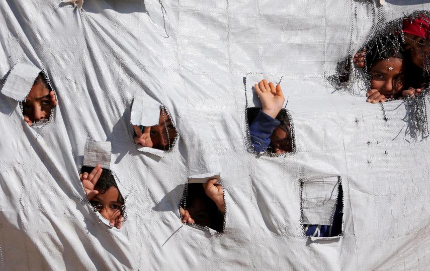 Children look through holes in a tent at the volatile al-Hol displacement camp, where nearly 70,000 people are in need of aid.