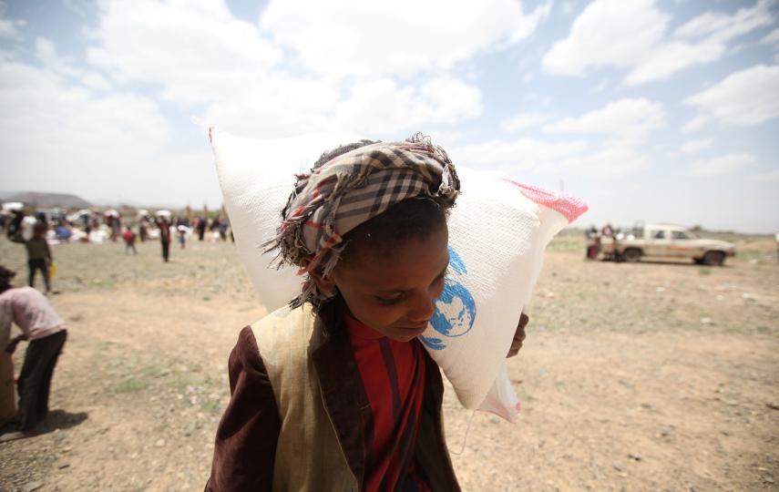 A boy carries food aid he received from the local charity, Mona Relief, on the outskirts of Sanaa, Yemen.