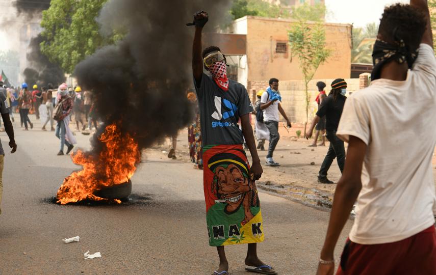 A protester gestures in front of burning tyres during a march against military rule in Khartoum on 12 May 2022.