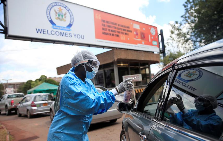 A health worker screens and sanitises visitors in Harare