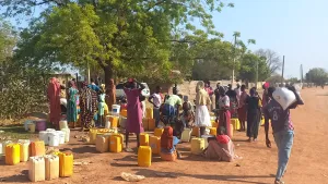 Residents of Abyei town gather at a water point and take shade under a tree. The arrival of displaced people from Sudan has strained local infrastructure in the disputed region. 