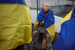 A Ukrainian prisoners of war (POW) returns after a swap. He wears the Ukrainian flag over his shoulders.