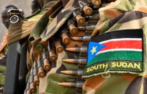 A close up photo showing the uniform and weapon of a South Sudanese soldier.