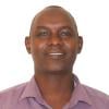 This is a headshot of Hussein Wario. He is pictured smiling and looking at the camera. He wears a burgundy button up shirt.