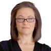 A headshot of Sarah W. Spencer, a consultant and researcher specialising in technology, foreign policy, and aid. She is facing the camera face-front and has a closed-mouth smile. She wears glasses and a black blouse.