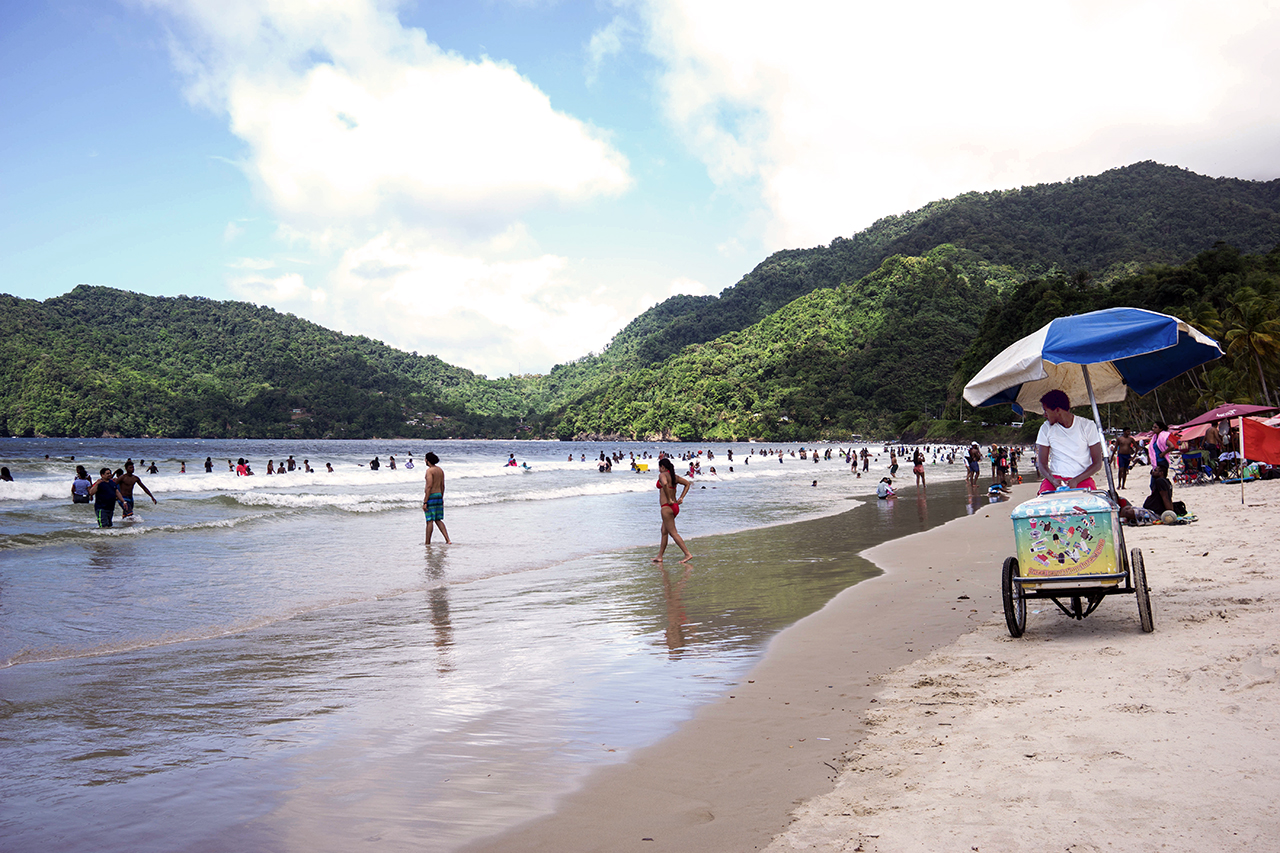 A beach scene with a vendor on a bike