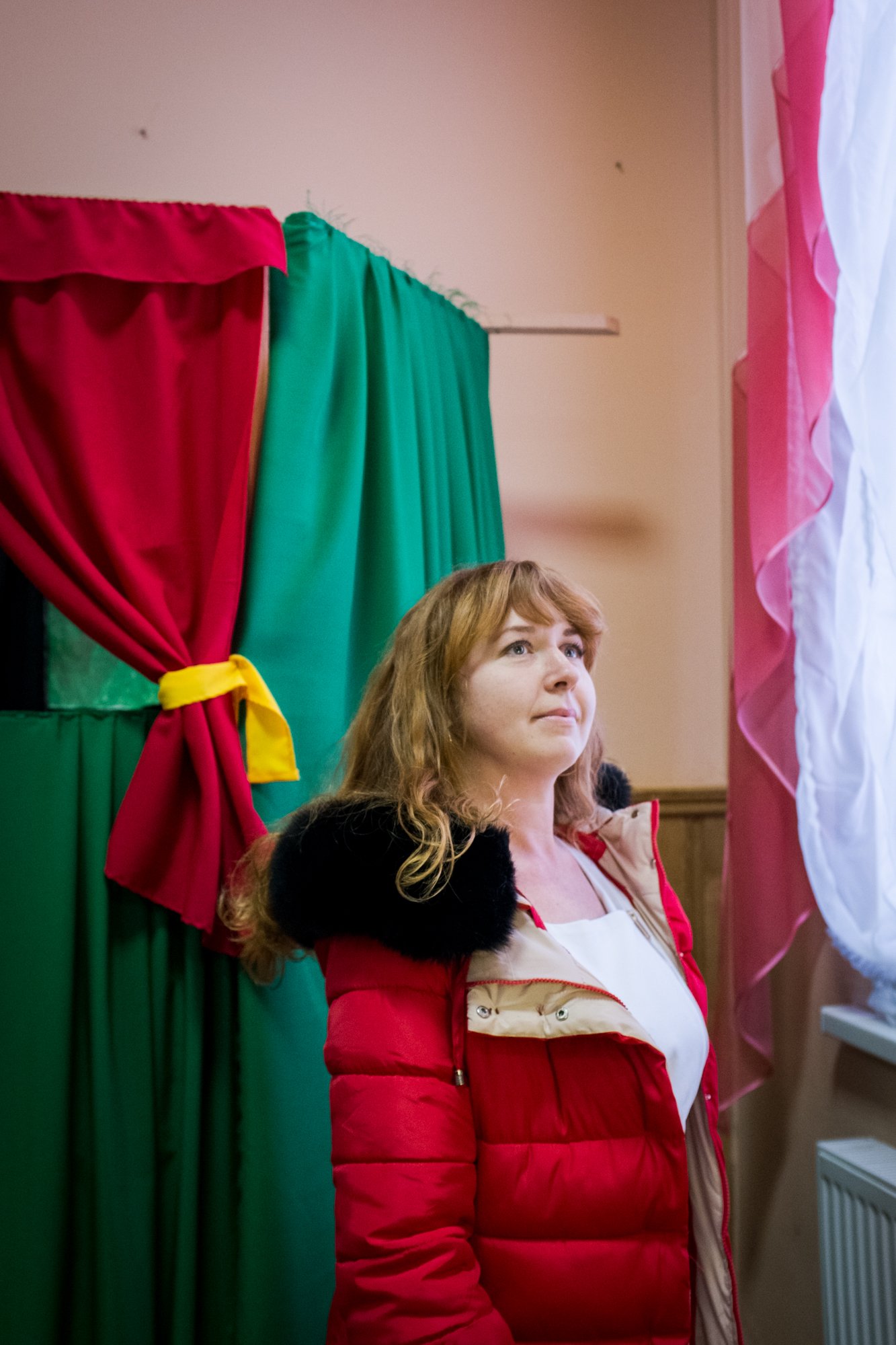 Photo of a woman in Ukraine in a puffy jacket in front of stage curtains