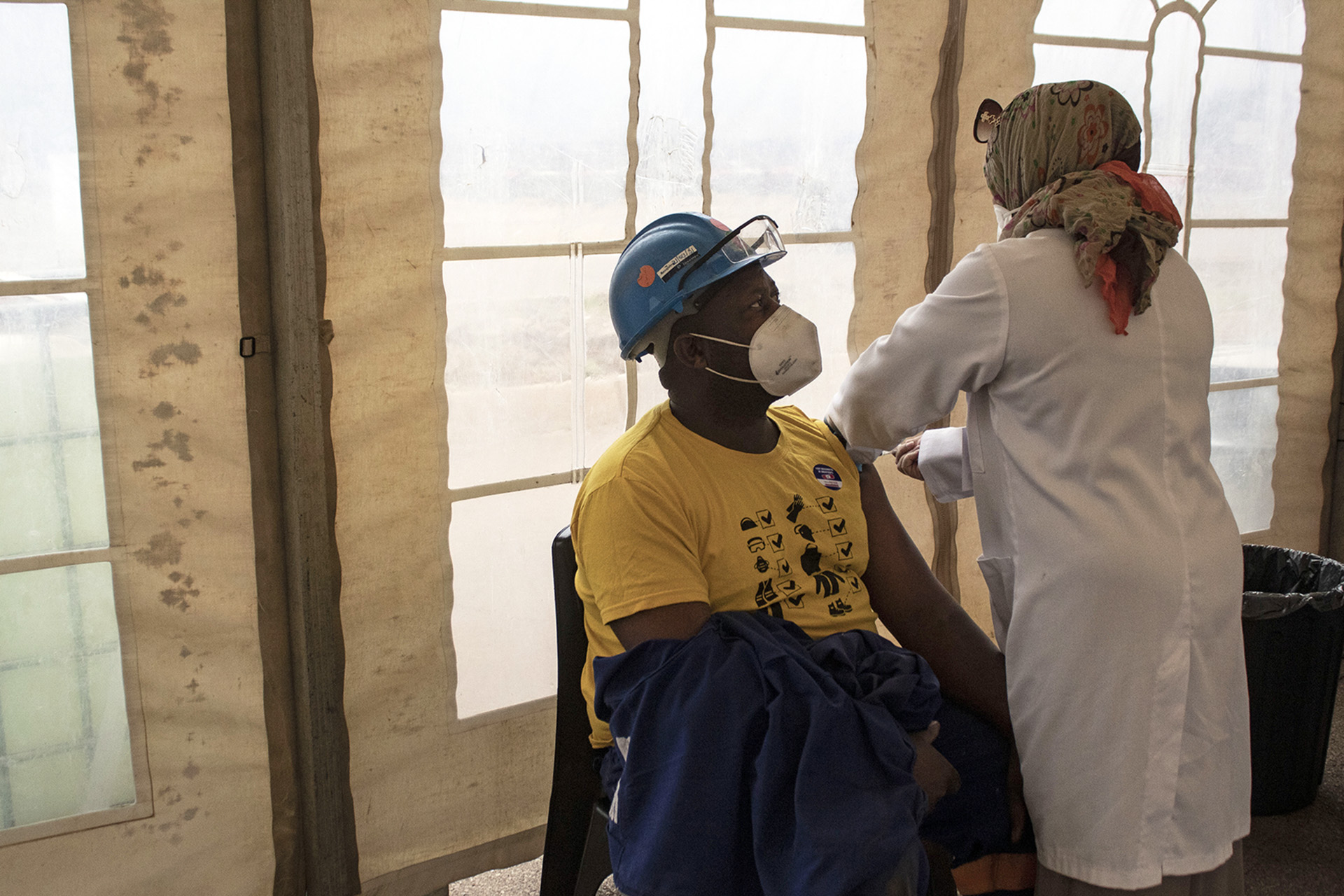 A man receives a vaccine in a temporary shelter.