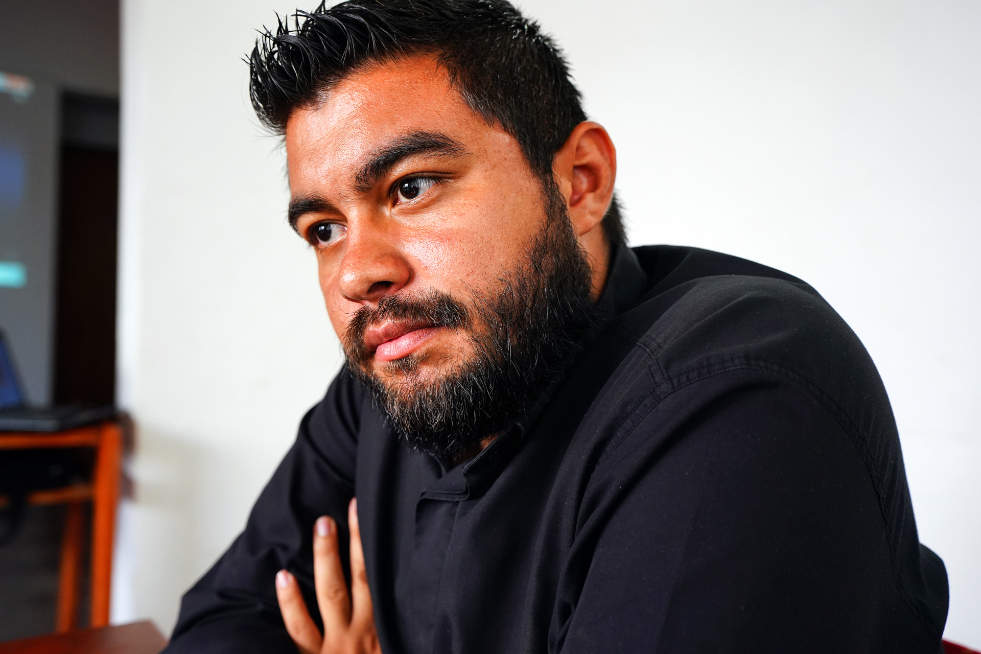 A portrait of a smiling, bearded man sitting 