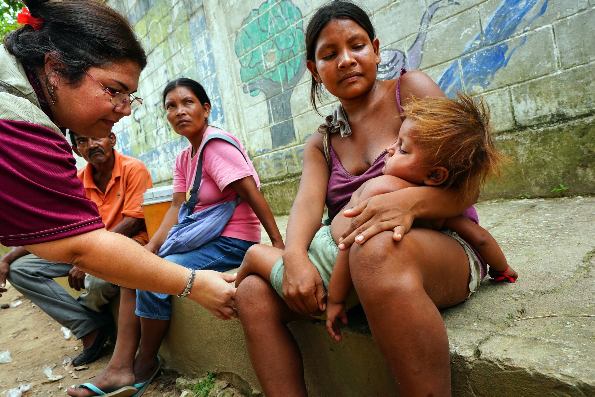 A doctor checks on a child in a woman's arms