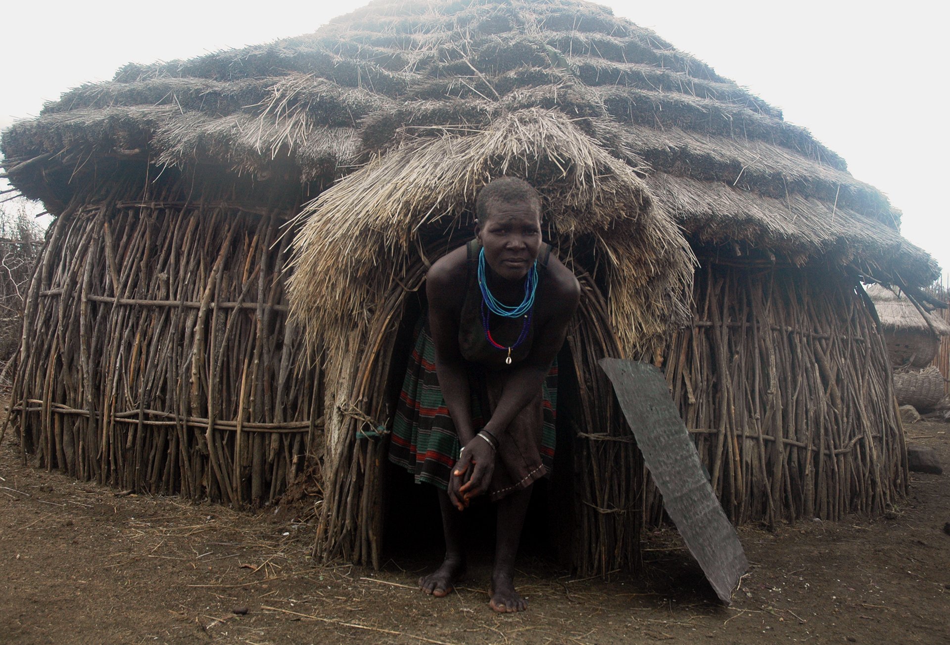 Veronica Korianga who lost a grandson getting out of her manyatta. Photo of a woman in Uganda exiting her manyatta.