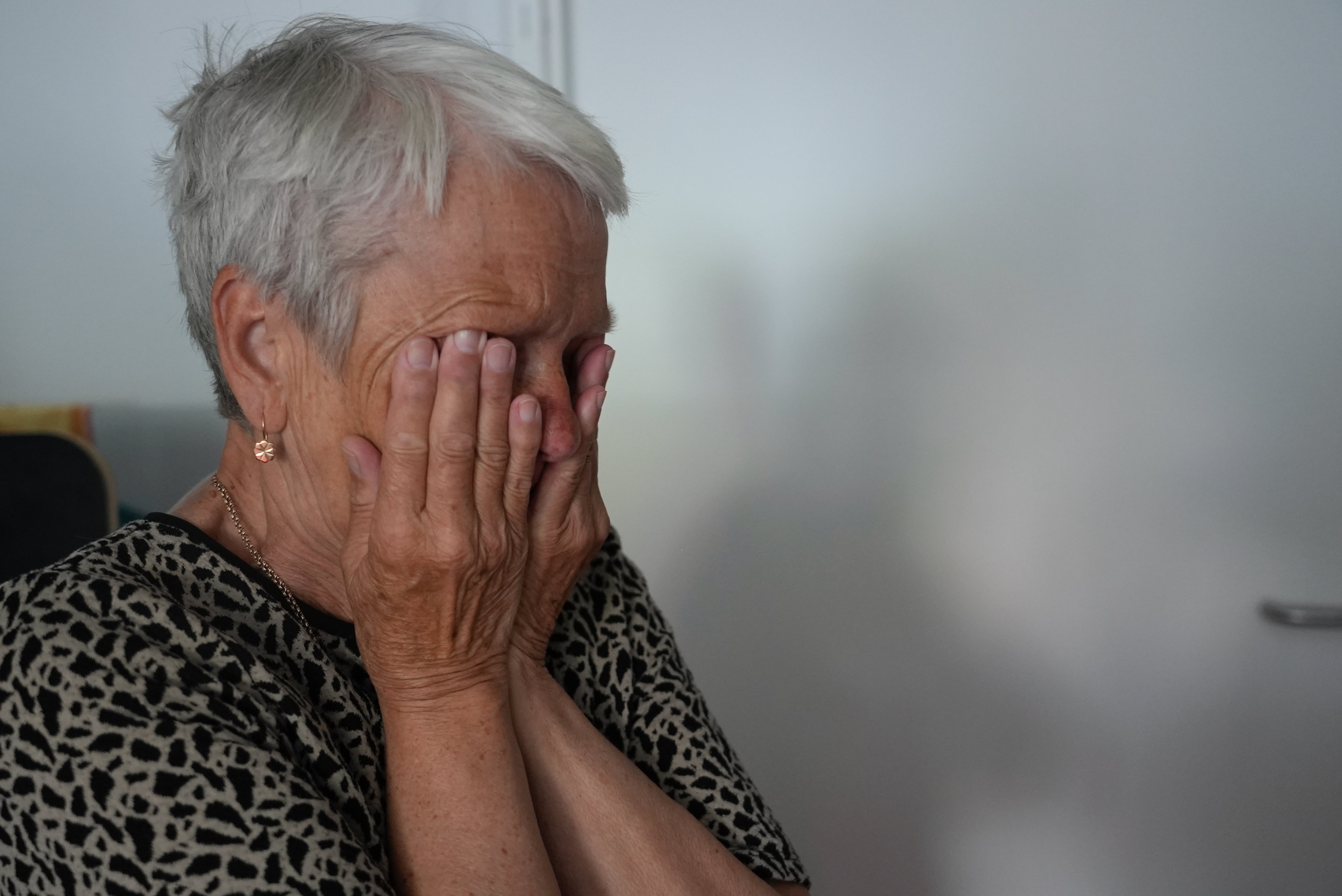 Natalia Zakharova's mother hides her face as she cries. The family's living in a one-room mobile housing site in a park in Lviv.