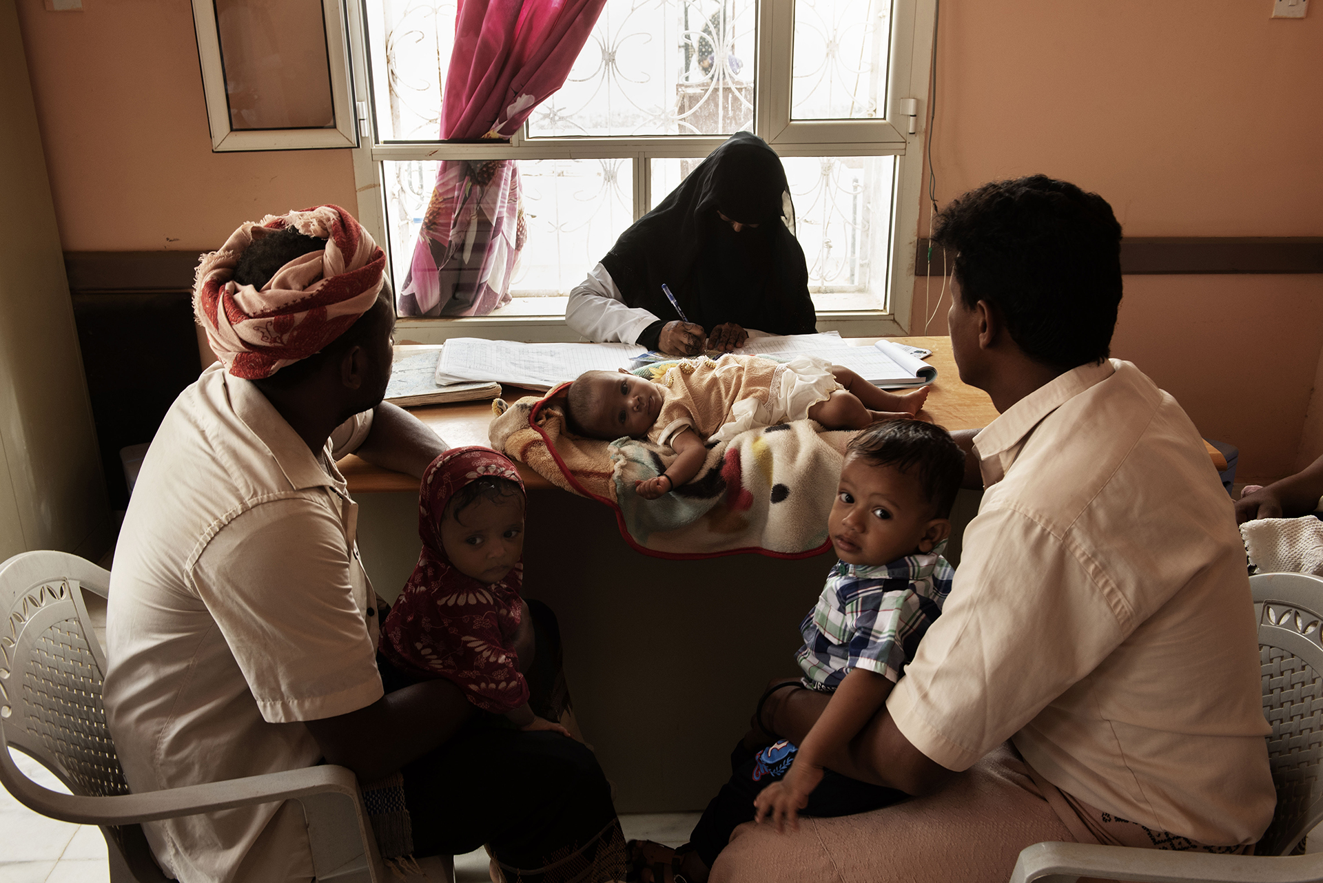 Photo of health clinic in Yemen with nurses, parents, and a child.