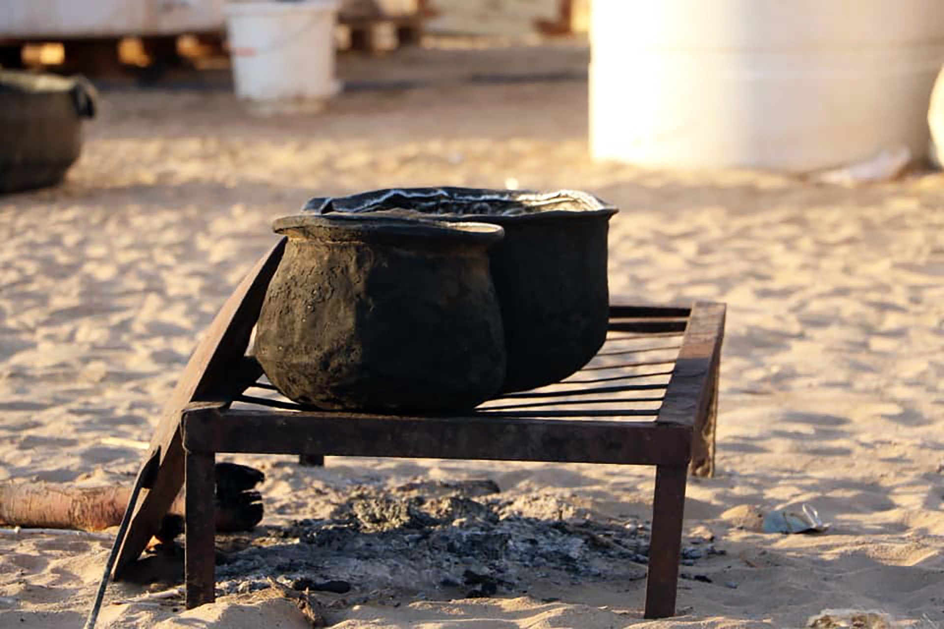 A pot rests on a makeshift stand above a shelter.